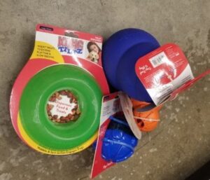 Options for toys for dogs with separation anxiety include interactive toys like the green ring, blue KONG, and other toys shown here.